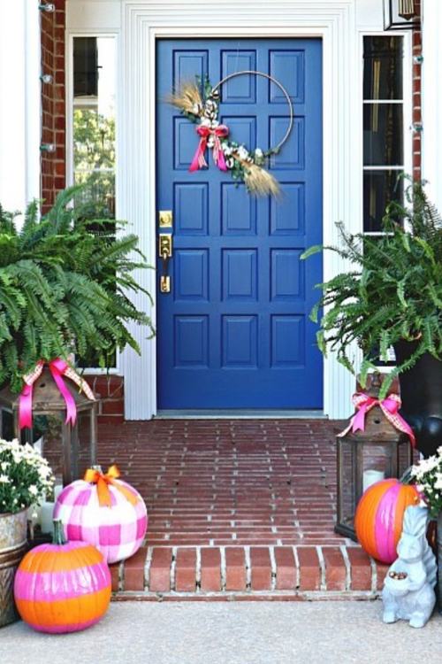 colorful fall front porch with blue door and pink pumpkins