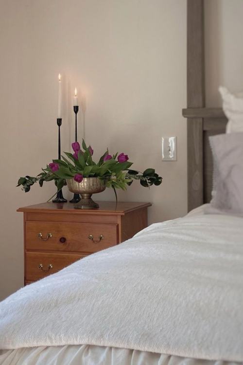 dresser at beside with two candle sticks and flowers