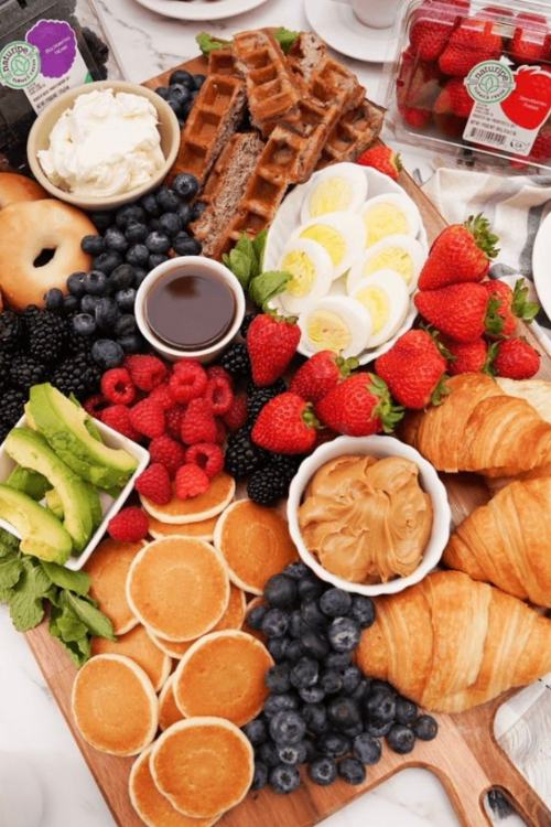 charcuterie board with croissants, pancakes, eggs and fruit