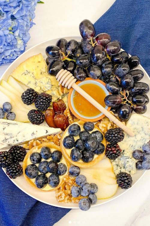 charcuterie board with grapes, cheese, and honey