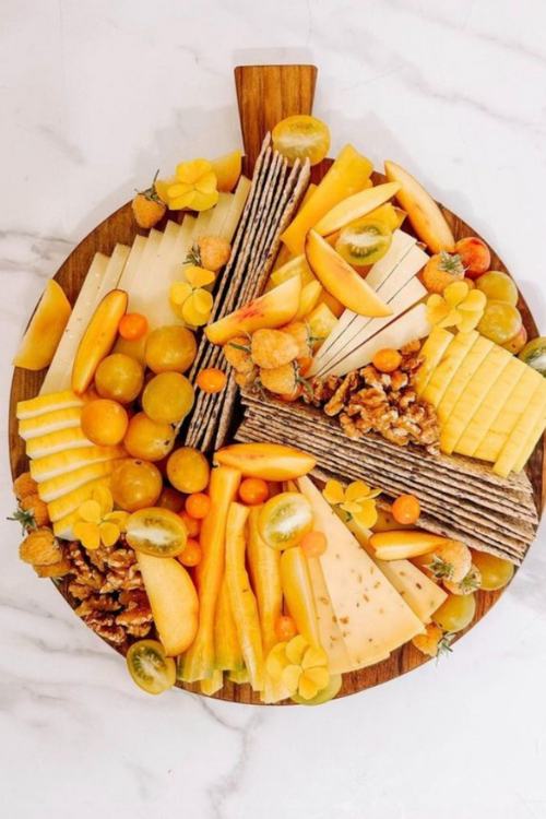 charcuterie board with yellow fruit, cheese, and crackers