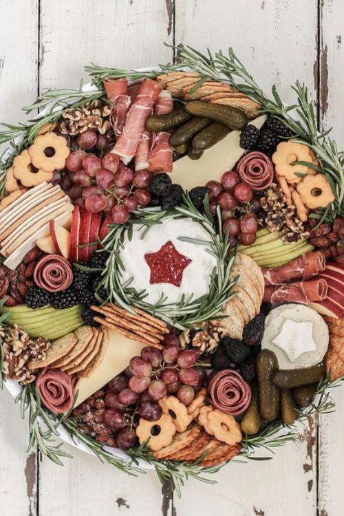 christmas charcuterie board with cheese, grapes, crackers, decorative rosemary