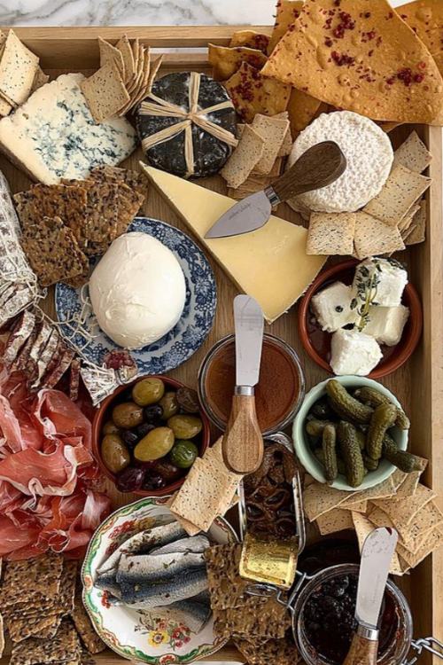 rustic charcuterie board with dishes of cheeses, honey, cured fish and meats