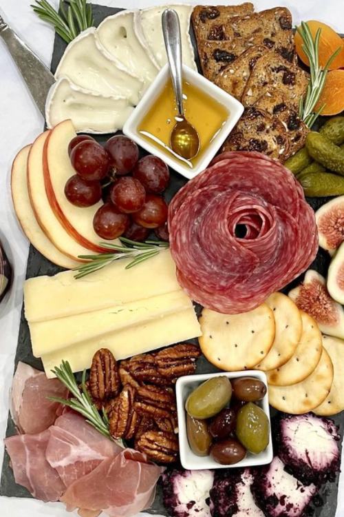 small charcuterie board with rose shaped cured meat, cheeses and honey