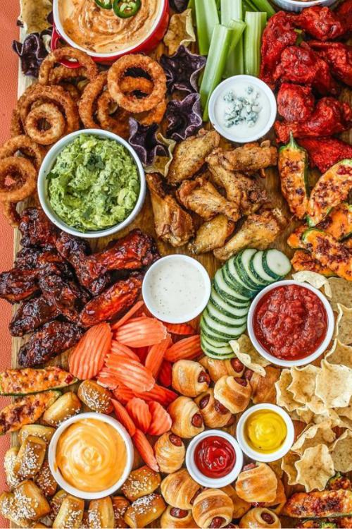 charcuterie board with bbq wings, chips, onion rings and dips