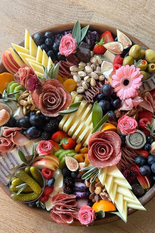 charcuterie board with floral shaped meats, fruit, and cheeses