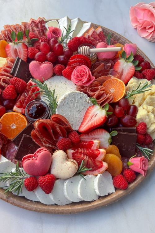 valentines charcuterie board with strawberries, cheese, heart shaped macaroons 