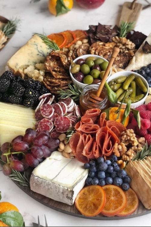 charcuterie board with a variety of meats, cheeses, olives and honey