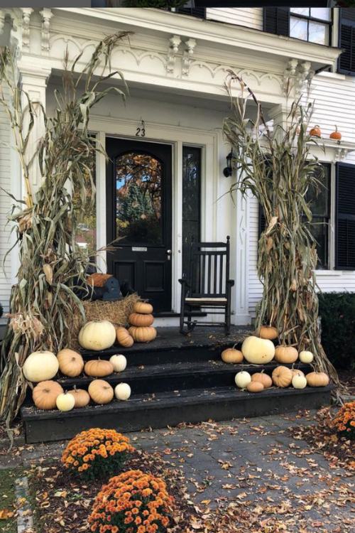 black fall front porch with white pumpkins and dried cornstalks