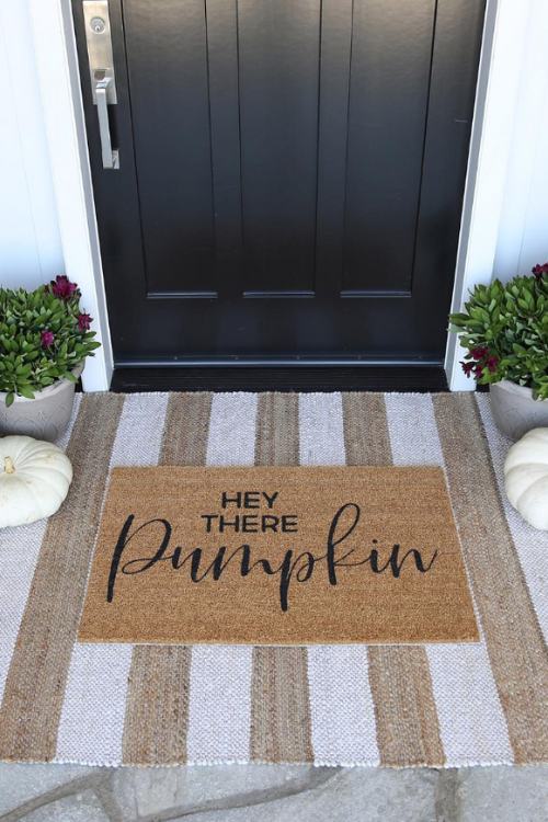 fall front porch with doormat that says "hey there pumpkin"