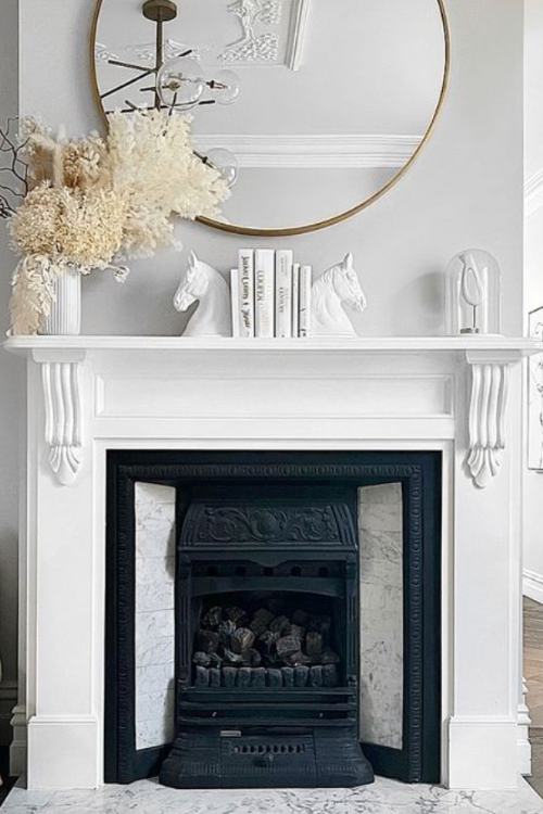 white fireplace with white decor and white dried flowers on mantel