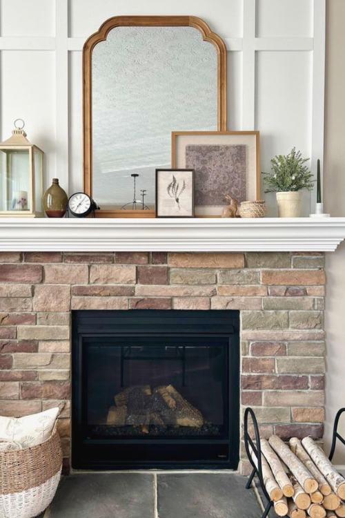 brick fireplace with mirror and small accessories on mantel