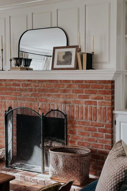 brick fireplace with mirror and antique books on the mantel