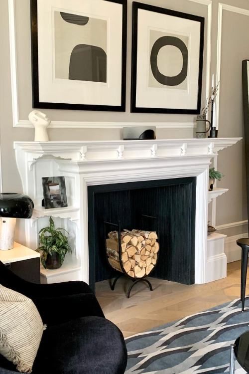 white fireplace with interior painted black and black and white paintings over mantel