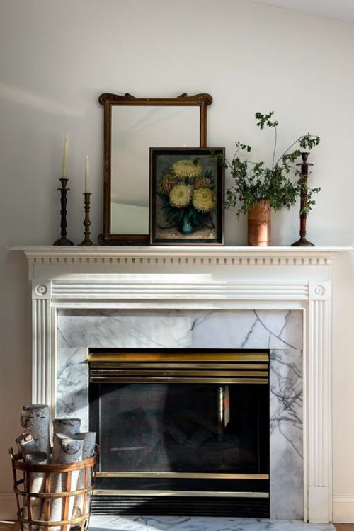 fireplace mantel with small painting leaning on antique mirror