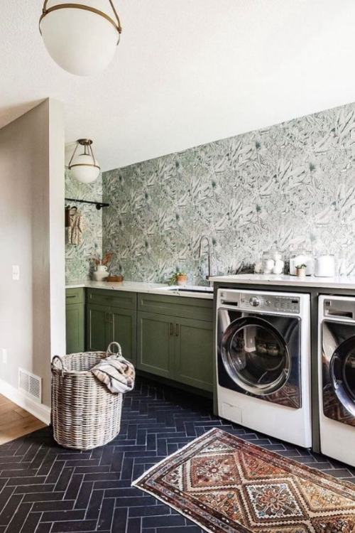 laundry room with green botanical wallpaper, green cabinets and dark herringbone floors