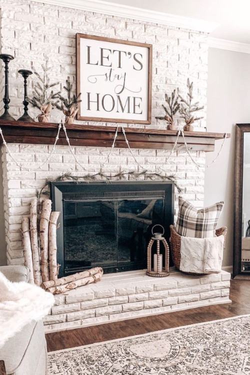 white brick fireplace with let's stay home sign on mantel