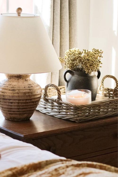 decorative basket tray on nightstand with vase of flowers and candle