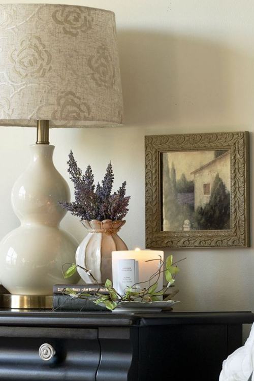 black nightstand with scented candle, vase of dried lavender and large lamp