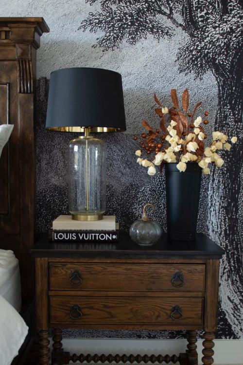 dresser nightstand with stack of black design books, black vase of dried flowers