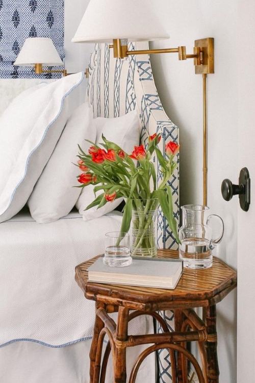 rattan nightstand with carafe of water and vase of tuilps