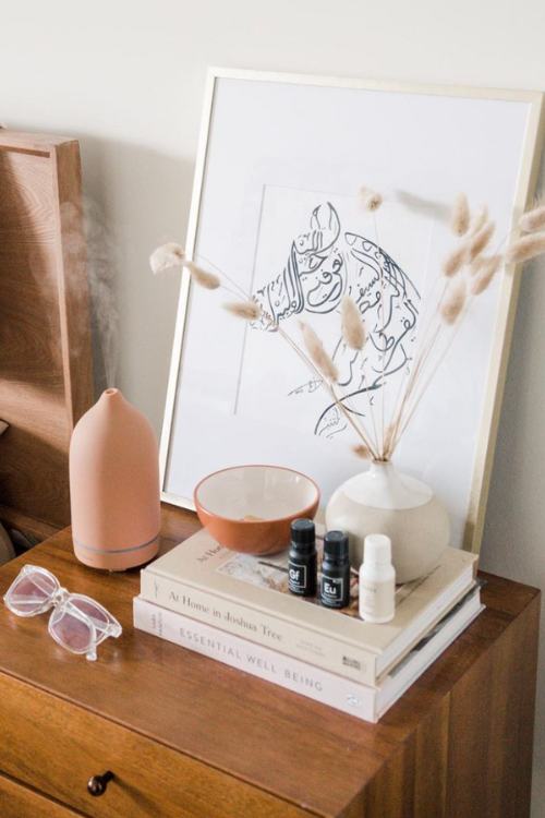 minimalist nightstand decor with abstract art and defuser next to stacked books