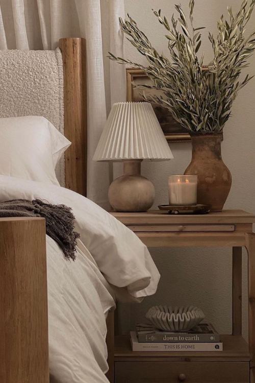 wooden nightstand with vase of leafy dry branches and lamp in earth tones