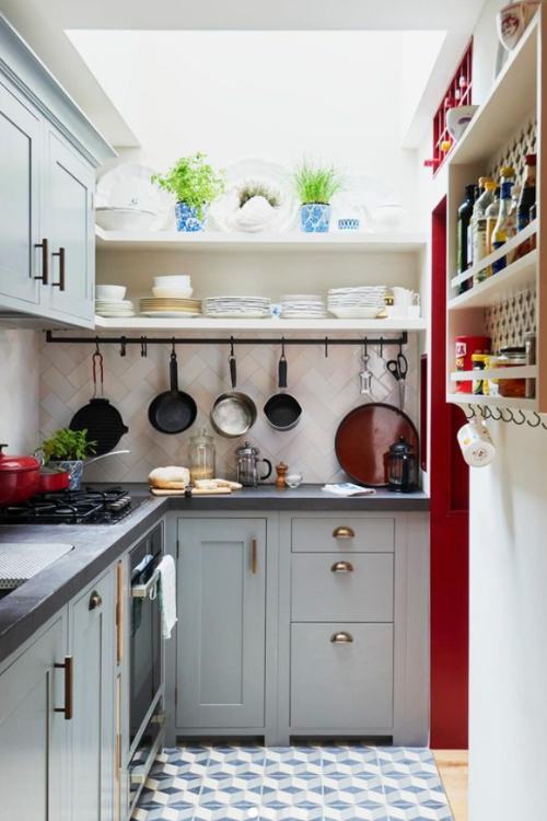 small kitchen with pots and pans hanging from hooks on the wall